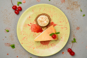 Cheesecake with cherry sauce and a scoop of ice cream on a yellow plate