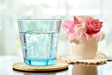 ソーダ水の入った青いグラスと小さなフラワーポッド