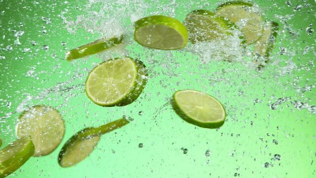 Super slow motion of lime pieces collision with water splashes, green background. Filmed on high speed cinema camera, 1000 fps.