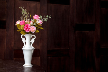 handcraft flowers in white ceramic vase with dark background.