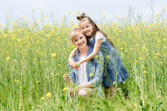 Happy family on a summer meadow. little girl child daughter hugging and kissing mother.Yellow field of rapeseed flowers. Freedom is a dream idea.