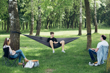 Fototapeta premium Social distancing. Small group of people enjoying picnic time in accordance with social distancing in summer park. Safety gatherings in new world.
