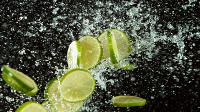 Super slow motion of lime pieces collision with water splashes, black background. Filmed on high speed cinema camera, 1000 fps.