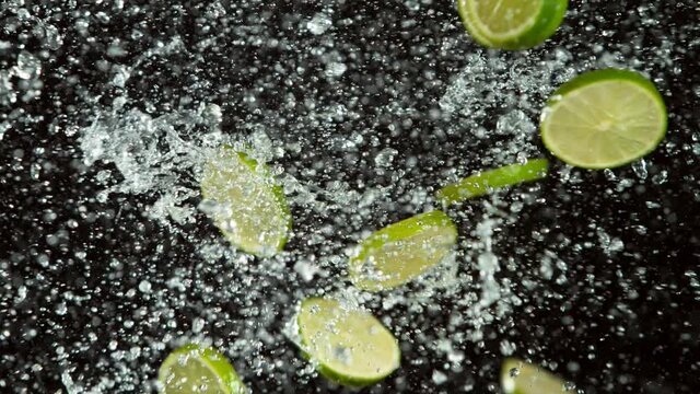 Super slow motion of lime pieces collision with water splashes, black background. Filmed on high speed cinema camera, 1000 fps.