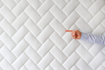 Cropped shot of man's hand pointing at copy space over white orthopedic mattress pattern. Hypoallergenic foam matress w/ proper spinal alingment & pressure point relief features. Background, close up.