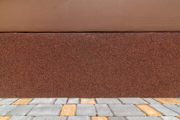 protective coating of facade of wall against moisture and water, closeup of building with moisture resistant coating of bitumen roll with stone crumb of grain and sidewalk made stone tiles, nobody.