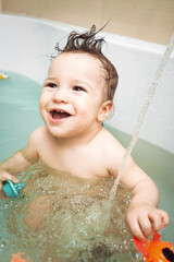 Cute happy little boy washing and playing in bathroom with toys. child's hygiene, healthy skin and body, happy lifestyle, carefree childhood concept