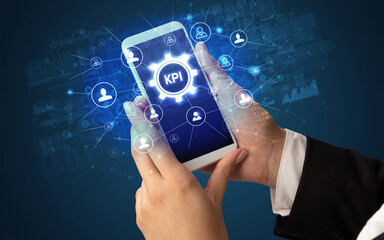 Female hand holding smartphone with KPI abbreviation, modern technology concept