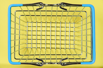 High angle shot of a retail or supermarket empty metal wire shopping basket with blue handles...