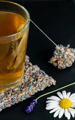 herbal tea in a glass cup with black background and hand knit coaster 