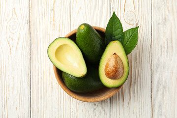 Bowl with fresh avocado on wooden background, top view