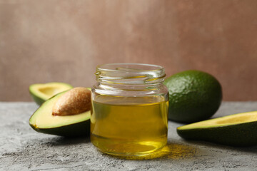 Ripe fresh avocado and oil on gray table, close up