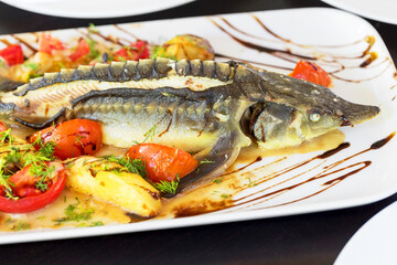 Grilled fish. Cooked fish is on the table .Grilled sturgeon fish. Grilled sturgeon fish. Sturgeon baked with vegetables. Healthy food. Soft selective focus