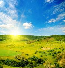 Picturesque hilly landscape. Green field and sunrise.