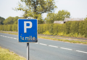 white P 1/4 quarter mile on a blue sign on a country road danger signage showing parking a less than a mile next to an english road directing drivers towards correct area to rest on the highway