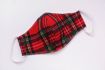 Red plaid cloth protective mask, isolated on white background. Covid-19 pandemic protection.
