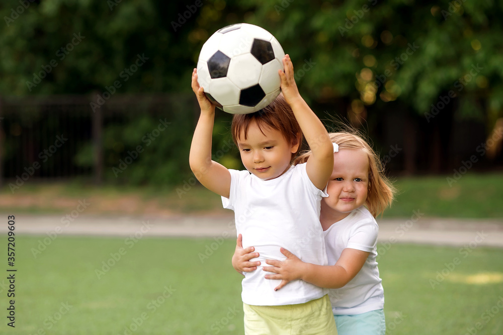 Wall mural gym lesson in kindergarten: two toddler children, boy and girl, playing together with soccer ball at