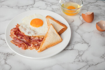 Breakfast with sunny side eggs, bacon and toast bread on a plate