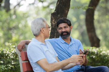 Son with old father talking at public park 