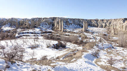 Fototapeta na wymiar Cappadocia cone-shaped rock formations near the city of Göreme with snow during winter in central Turkey.