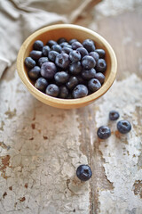Image of blueberries in wooden bowl on rustic village table.