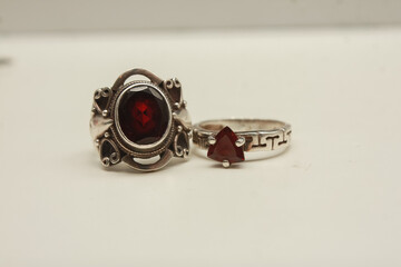 Two silver rings with natural red garnet stone on a white background.