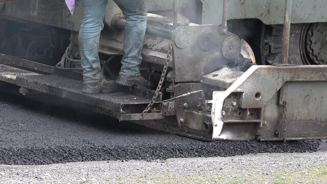 Builder On Asphalting Paver Machine During The Reopening After Covid 19 Lockdown