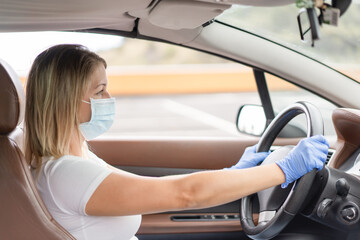 Young blond northern woman driving the car and wearing protective face mask and gloves - Focus on the face mask - Concept of the new normality