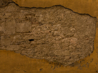 Old brick or stone wall with fallen stucco. Grunge texture of antique architecture. Abstract frame or background.