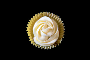 Viewed from above a rose shaped yellow cupcake on a black bacground
