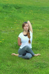 Young woman of European appearance does yoga in summer nature