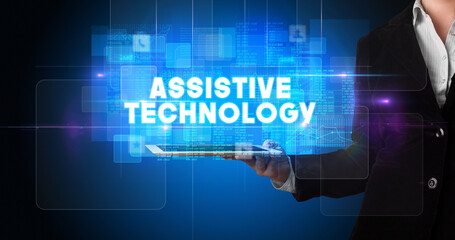 Young business person working on tablet and shows the inscription: ASSISTIVE TECHNOLOGY