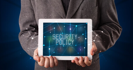 Young business person working on tablet and shows the digital sign: SECURITY POLICY