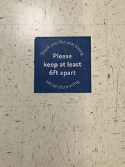 Blue sign asking people to keep a minimum distance of each other on the wall