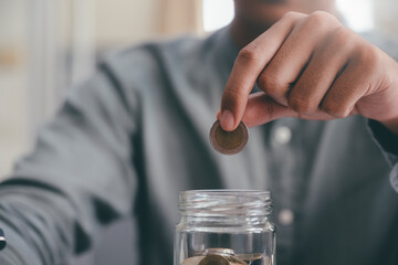 Closeup male hand holding coins putting in glass.