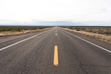 A paved straight highway disappearing into a mountain in fog.