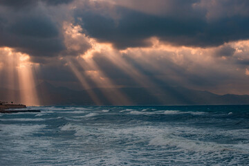 sunset over the sea with rays of light between storm clouds
