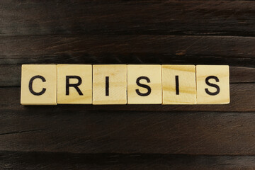 Crisis word of square letters on a dark wooden background