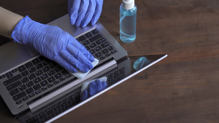 Woman cleans keyboard with antibacterial napkin. Doctor disinfects computer work surface with an antiseptic. Preventive measures or cleaning procedures during the coronavirus pandemic.