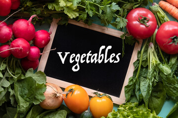 Fresh vegetables around black desk with text "Vegetales"on blue background