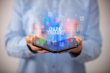 Young man holding a foldable smartphone with ONLINE TRAINING inscription, educational concept