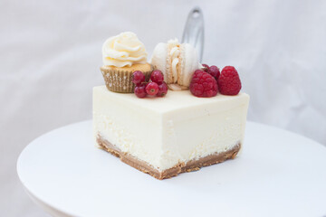 Slice of classic vanilla cheesecake New York with fresh raspberry and red currant on white cakestand.