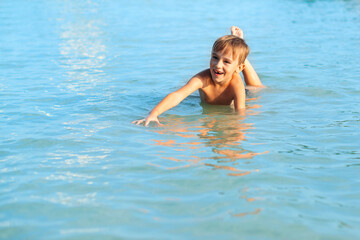 Happy child playing in the sea. Cute boy swimming in water. Summer vacation.
