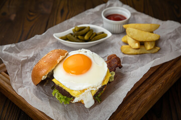 hamburger with cutlet, cheese, sauces, salad and french fries on a wooden background 
