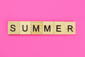 word summer made of wooden letters on a pink background