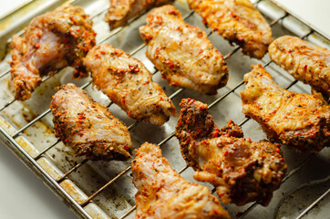 Raw chicken wings with a rendang style rub made with chilli and garlic on the grill tray
