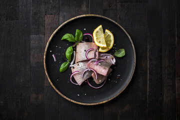 Fototapeta na wymiar marinated herring with red onion, lemon and basil