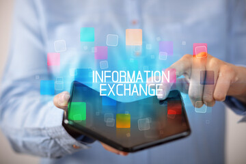 Young man holding a foldable smartphone with INFORMATION EXCHANGE inscription, educational concept