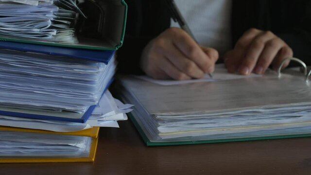 defocused accountant working in office at night, dark binders full of documents