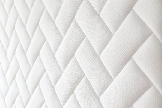 Close up shot of white orthopedic mattress top side surface pattern with a lot of copy space for text. Hypoallergenic foam matress for proper spinal alingment and pressure point relief. Background. © Evrymmnt